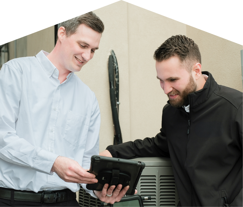 A Peel technician in a white shirt shows service details on a tablet to a smiling client in a black jacket, standing beside an AC unit outside a beige building. A Peel technician in a white shirt shows service details on a tablet to a smiling client in a black jacket, standing beside an AC unit outside a beige building.