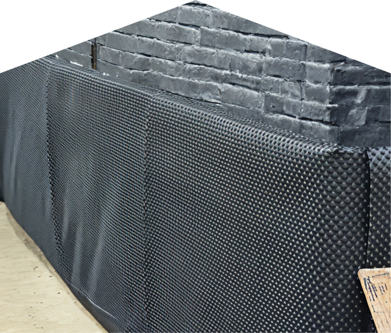 Exterior basement waterproofing completed by Peel, showing a sealed foundation wall with dimpled waterproof membrane partially installed on a brick surface, preventing moisture infiltration. Exterior basement waterproofing completed by Peel, showing a sealed foundation wall with dimpled waterproof membrane partially installed on a brick surface, preventing moisture infiltration.