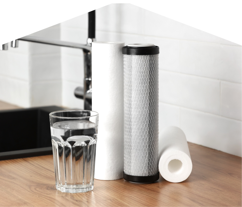Set of Peel water filtration cartridges placed beside a clear glass of water on a kitchen countertop, with a sink and modern faucet in the background. Set of Peel water filtration cartridges placed beside a clear glass of water on a kitchen countertop, with a sink and modern faucet in the background.