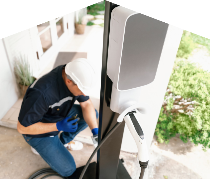 Home service electrician from Peel installing an EV charger fixed to a vertical post near a residential entryway.