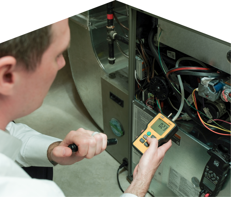 Peel HVAC specialist performing furnace repair on a heating system, using a digital manometer to check pressure. Peel HVAC specialist performing furnace repair on a heating sy