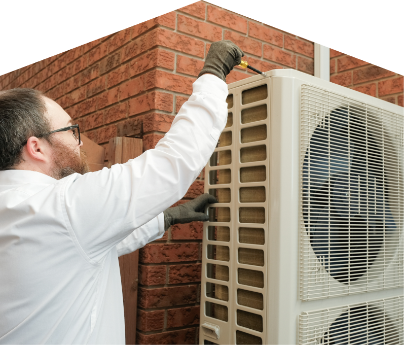 Peel HVAC specialist using a screwdriver to complete a heat pump installation beside a brick wall. Peel HVAC specialist using a screwdriver to complete a heat pump installation beside a brick wall.