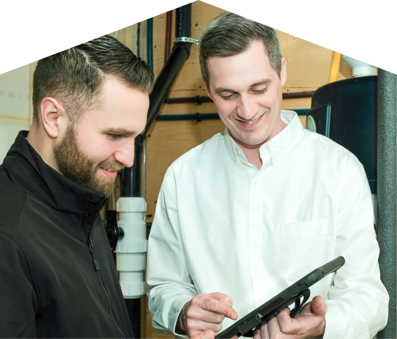 Peel specialist reviewing maintenance plan options with a smiling homeowner using a tablet, inside a utility room with visible piping. Peel specialist reviewing maintenance plan options with a smiling homeowner using a tablet, inside a utility room with visible piping.