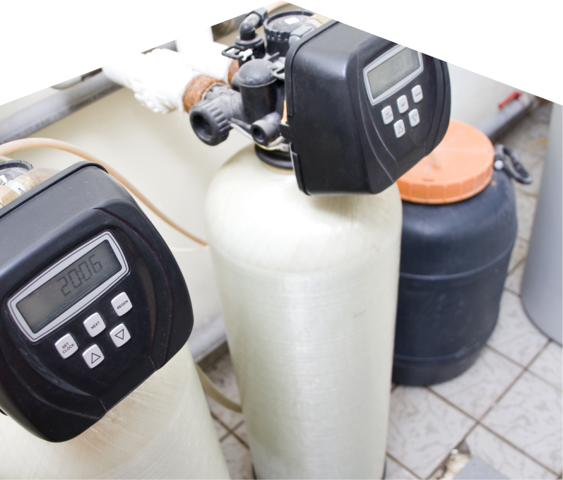 Peel water softener installation showing dual resin tanks with digital control heads and a brine tank in a tiled utility area.