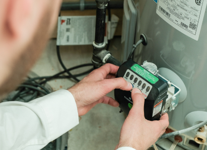 A Peel technician adjusts the control module on a residential water heater, verifying proper operating settings. A Peel technician adjusts the control module on a residential water heater, verifying proper operating settings.