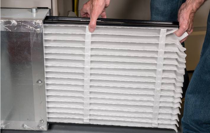 man inserting a new filter into his furnace